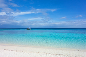 White clouds and Banca boat on blue sky over calm sea. Clear blue water with fantastic white sand beach. Summer outdoor nature holiday serenity. Kalanggaman Island, Philippines. Background,