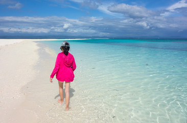 Fototapeta na wymiar Back of young Asian girl in pink jacket walking on perfect white sand beach and clear blue sea. Summer outdoor nature holiday serenity. Kalanggaman Island, Philippines. Background, copy space.