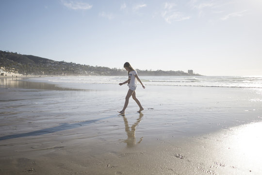 Full length side view of girl walking at beach on sunny day
