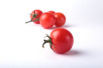 Sprig of fresh tomatoes with green leaves isolated on white background.