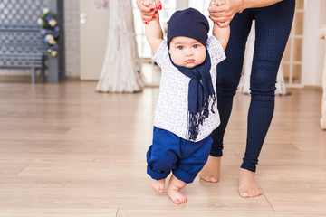 baby taking first steps with mother help
