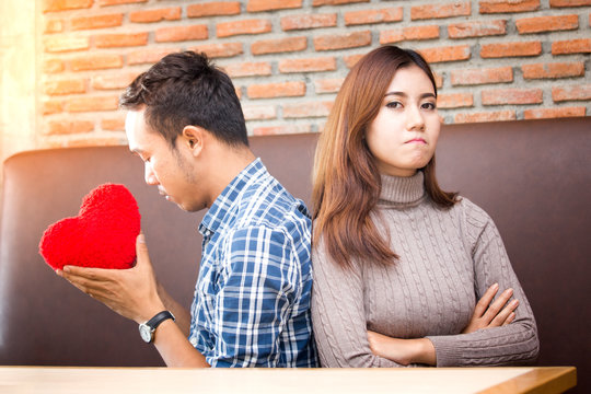 Portrait of a young couple asian man holding red heart to give for woman.