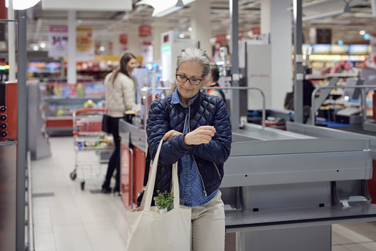 Smiling mature woman walking with shopping bag at supermarket