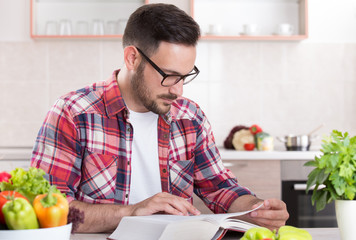 Man reading recipe book in kitchen