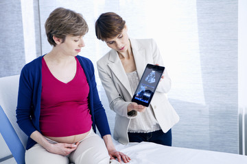 Doctor showing ultrasound scans to a pregnant woman