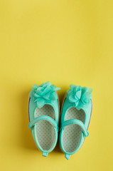 Turquoise shoes for baby girl over yellow background