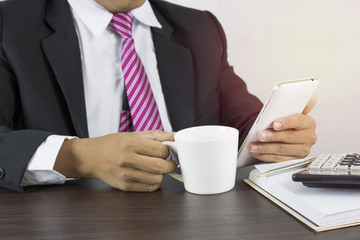 business man look information,  use phone and  drink cup of coffee in work place
