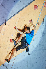 man climber climbs with rope on climbing gym. man mekes hard wide move. Climbing competition
