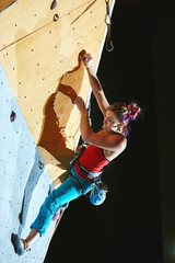 woman climber climbs with rope on climbing gym. woman mekes hard wide move. Climbing competition