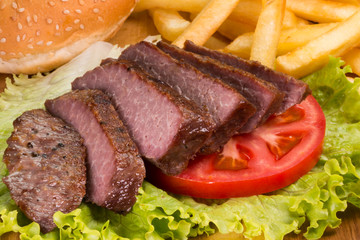 Grilled beef steaks, French fries and vegetables close-up