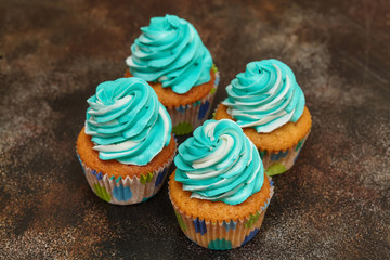 Cupcakes with turquoise and white buttercream frosting on brown background