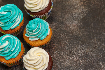 Cupcakes with turquoise and white buttercream frosting on brown background