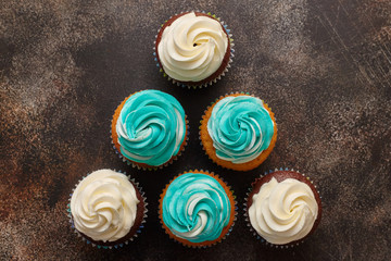 Cupcakes with turquoise and white buttercream frosting on brown background