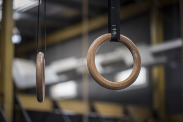A pair of gymnastic  rings hanging in a gym with an out of focused or blurred background 