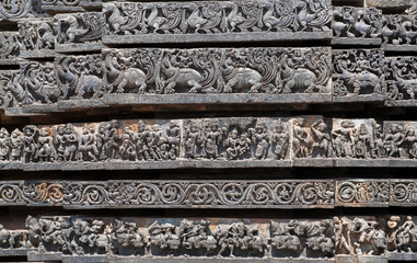 Patterns of the Hindu temple walls with elephants, lions, scrolls, horses, vedic and puranic scenes, mythical beasts and swans. 12th centur Hoysaleshwara temple in Halebidu, India.