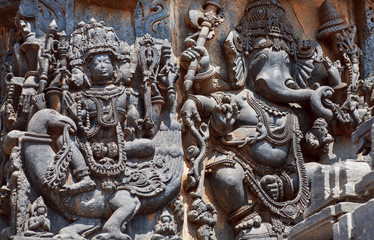 Ancient relief with Lord Brahma on swan and Ganesh, the Hindu temple walls with patterns, vedic scenes, mythical beasts and gods. 12th centur Hoysaleshwara temple in Halebidu, India.