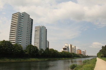 Fototapeta premium Regnitz-Radweg am Main-Donau-Kanal vor der Skyline der Wohnhochhäuser in Erlangen-Büchenbach