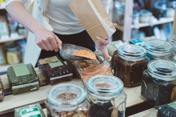 Woman puts lentil seeds into a paper bag