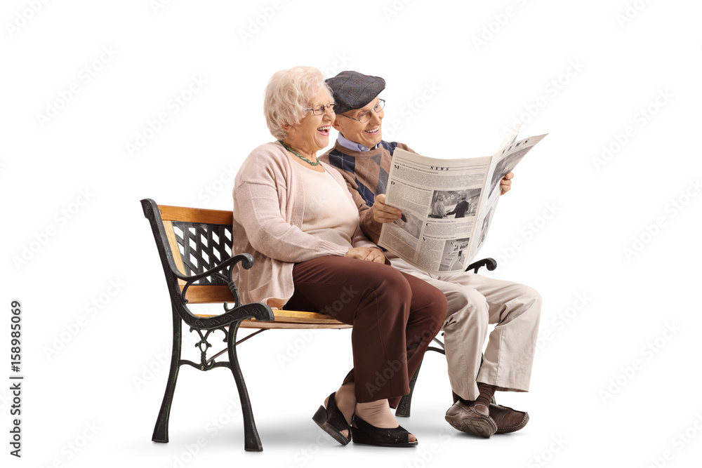 Canvas Prints Joyful senior couple sitting on bench and reading newspaper together