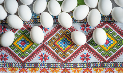 White chicken eggs wrapped in burlap next to a basket on a wooden table