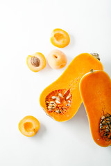 Butternut squash halved with apricots on white background with copy space. Organic food concept.