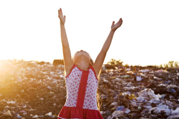 A little girl raised her hands in the sky in the sunlight