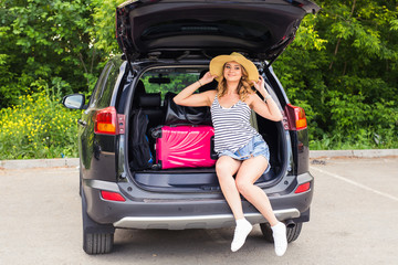 Happy woman with luggage in car trunk. Travel concept