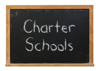 Obraz premium Charter Schools written in white chalk on a black chalkboard isolated on white