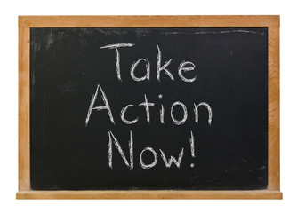 Take Action Now written in white chalk on a black chalkboard isolated on white