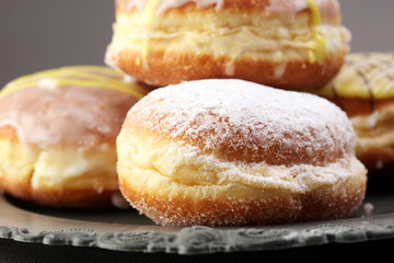 German donuts - berliner with jam and icing sugar in a tray on a grey background.