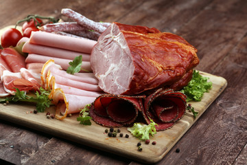 Food tray with delicious salami, pieces of sliced ham, sausage, tomatoes, salad and vegetable - Meat platter with selection