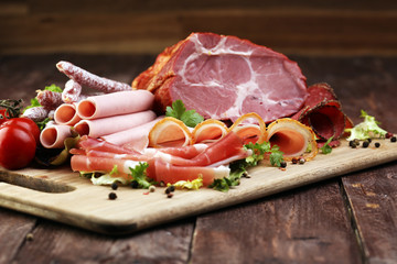Food tray with delicious salami, pieces of sliced ham, sausage, tomatoes, salad and vegetable - Meat platter with selection