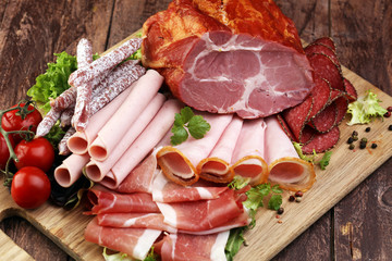 Food tray with delicious salami, pieces of sliced ham, sausage, tomatoes, salad and vegetable - Meat platter with selection