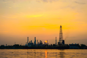 Fototapeta premium Oil refinery petrochemical industry with river sunrise