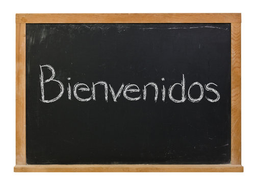 Bienvenidos written in white chalk on a black chalkboard isolated on white