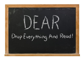 DEAR drop everything and read written in white chalk on a black chalkboard isolated on white