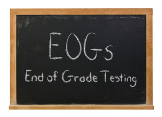 Fototapeta premium EOGs End of Grade Testing written in white chalk on a black chalkboard isolated on white