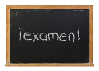 Exam written in Spanish in white chalk on a black chalkboard isolated on white