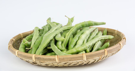 Green bean in a bamboo basket isolated on white background