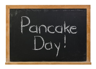 Fototapeta premium Pancake Day written in white chalk on a black chalkboard isolated on white 