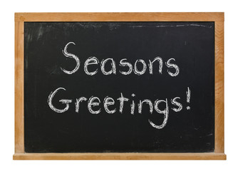Obraz premium Seasons Greetings written in white chalk on a black chalkboard isolated on white