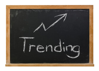 Obraz premium Trending written in white chalk on a black chalkboard isolated on white