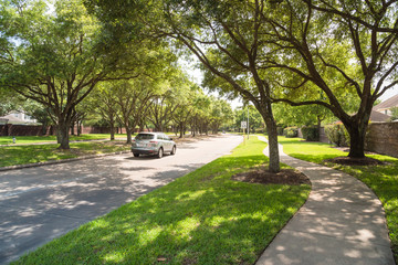Side view of asphalt road, street in suburban residential area with lot of green trees in Katy, Texas, US. America is an excellent green and clean country. Environmental and transportation background. © trongnguyen