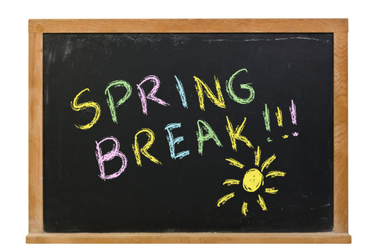 Spring Break with a sun written in colorful chalk on a black chalkboard isolated on white