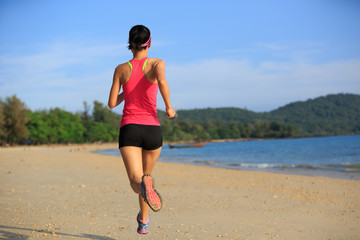 Healthy lifestyle young fitness woman running at sunny beach