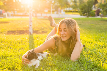 Pets and owner concept - Beautiful girl playing with a cat in the grass.