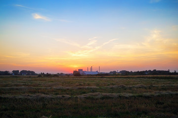 Beautiful sunset. Sun rays in the picturesque sky and rural meadow.