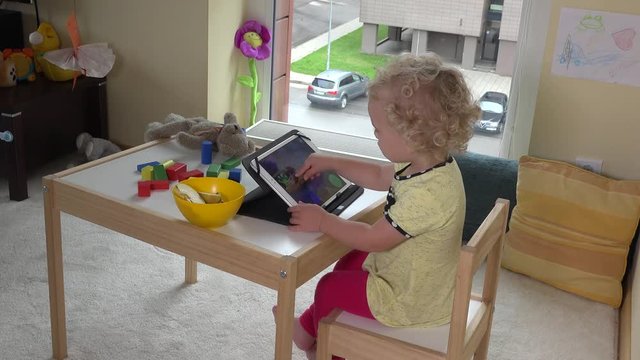 Toddler child playing with tablet. Computer addict girl