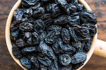 Organic Dried Raisins or Grape in wooden ladle.
