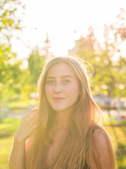 Attractive young woman enjoying her time outside in park with sunset in background